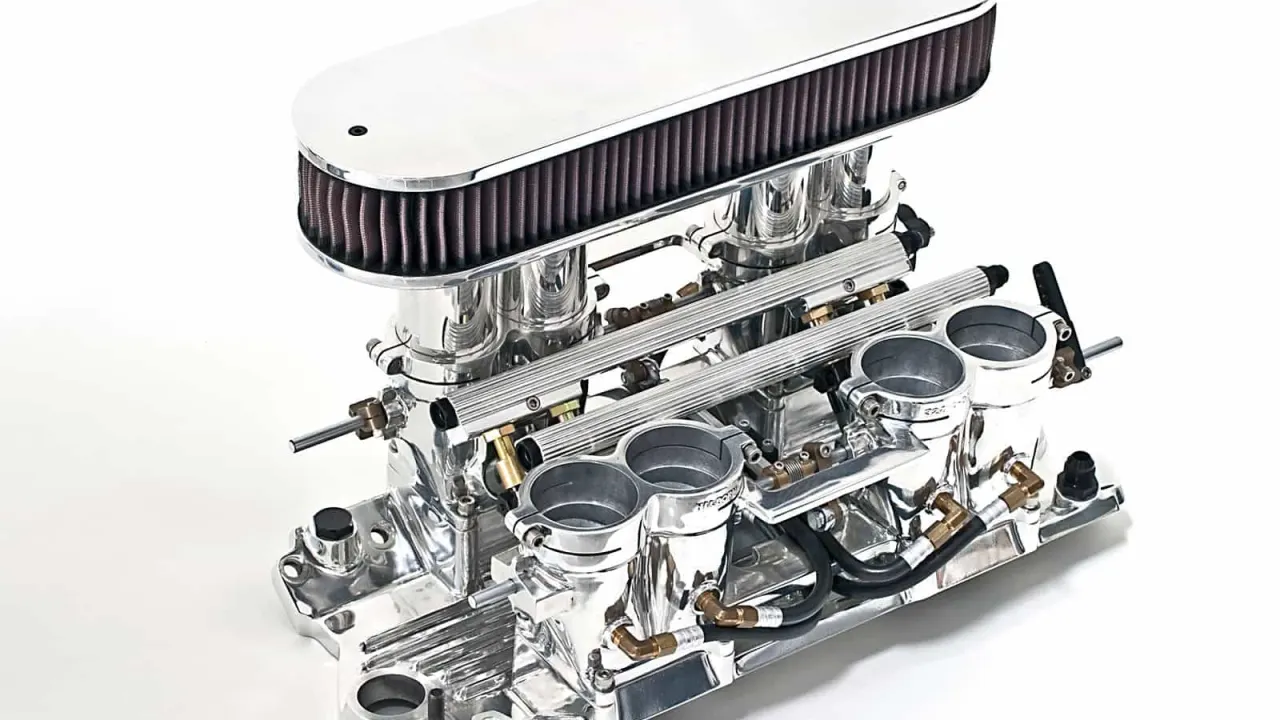 A polished intake manifold fitted with an air filter and twin carburetors