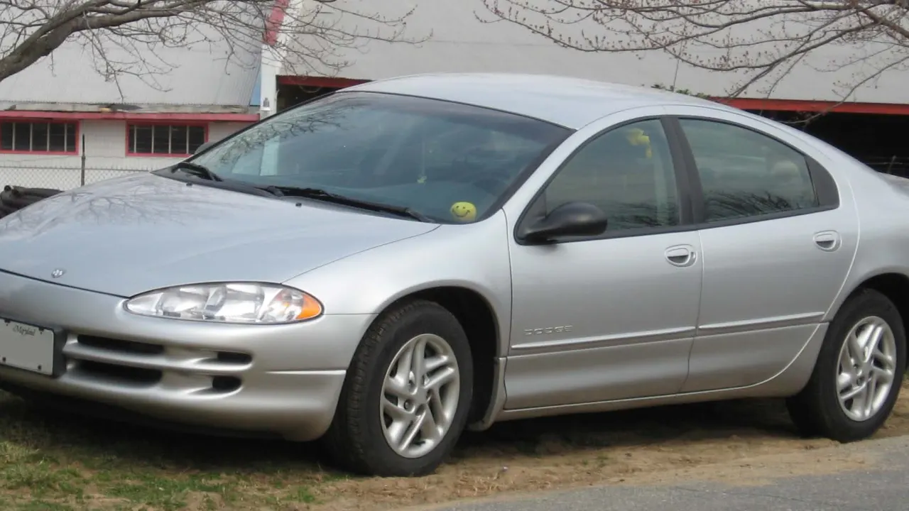 A silver Dodge Intrepid sedan parked beside a barn