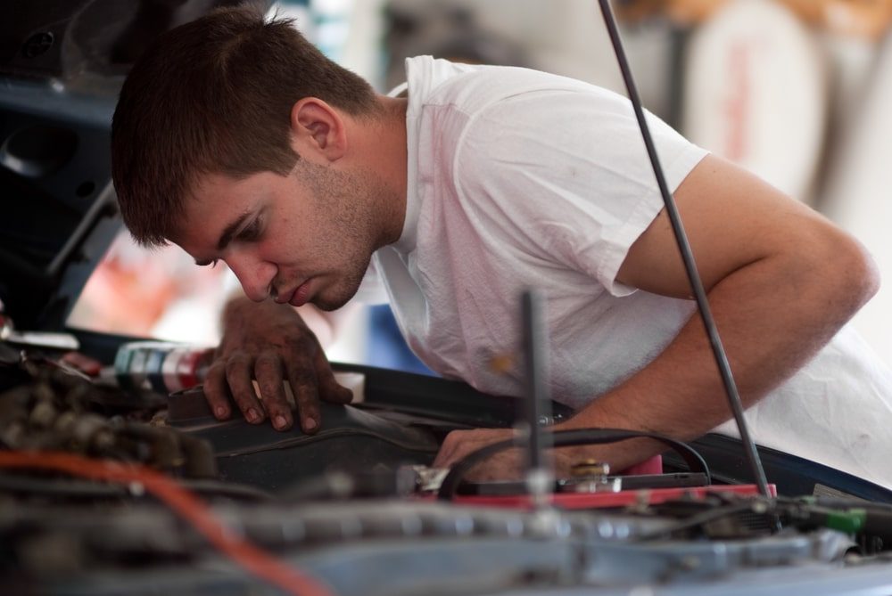 Man looking underneath the bonnet of a car