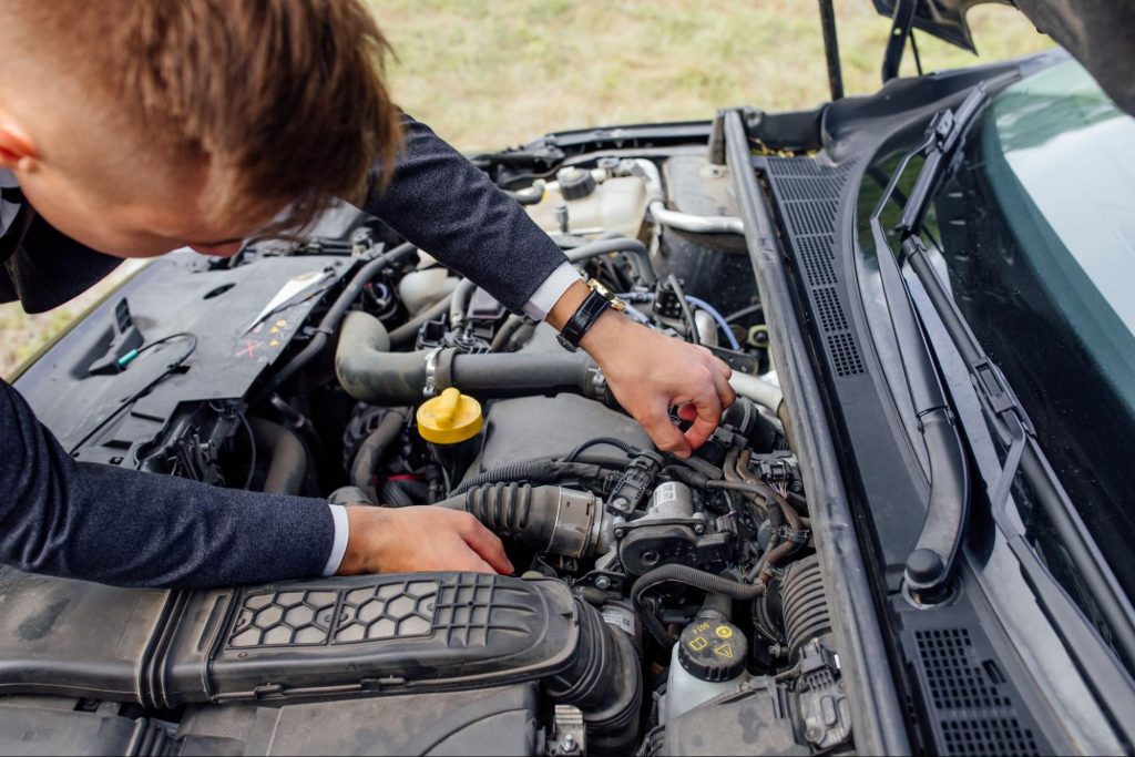 Mechanic performing ECM flash and vehicle computer testing on a car in a repair shop.