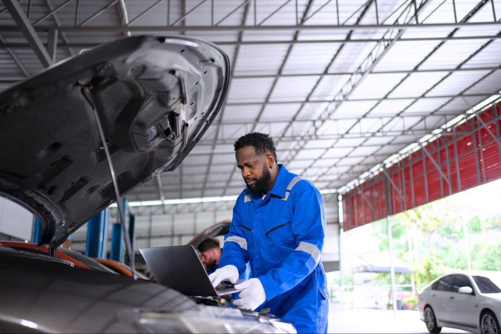 Technician inspecting engine bay components with scan tools before PCM reprogramming,  where can i get my pcm reprogrammed

